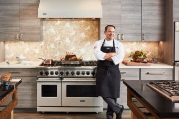 A chef standing next to a viking range.
