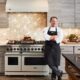 A chef standing next to a viking range.