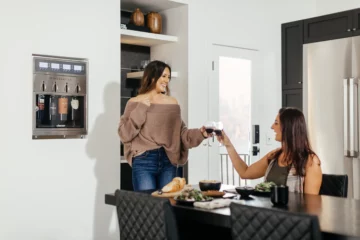 Two women enjoy glasses of wine from a Dacor wine dispenser