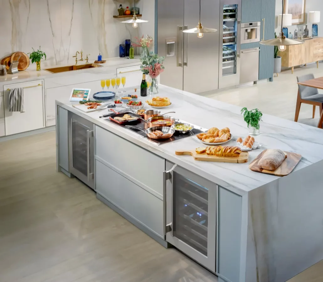 Modern Thermador kitchen featuring Liberty induction cooktop on marble island with integrated wine refrigerator and Freedom column refrigeration, showcasing complete appliance package eligible for free gifts promotion