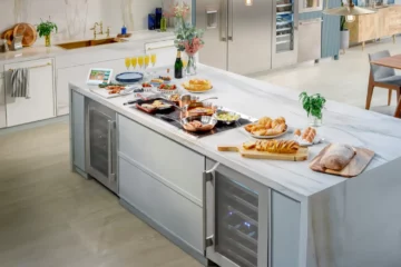 Modern Thermador kitchen featuring Liberty induction cooktop on marble island with integrated wine refrigerator and Freedom column refrigeration, showcasing complete appliance package eligible for free gifts promotion