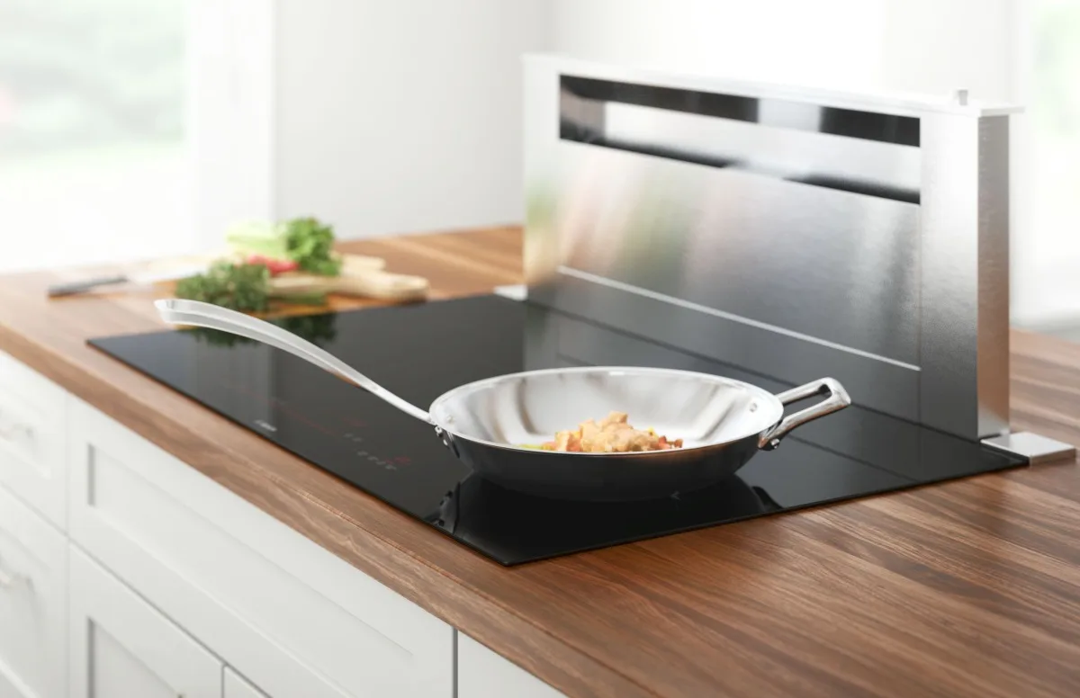 Bosch 800 Series induction cooktop with stainless steel pan on walnut countertop