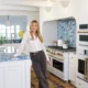 Kate Hudson standing in her blue jean baby kitchen with Sodalite Blue Quartzite countertops and Cafe Matte White appliances with Brushed Brass hardware