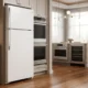 White GE GTS18HGNRWW top-freezer refrigerator in a luxury appliance showroom