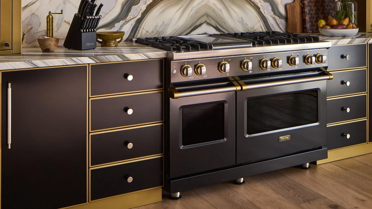 Black Viking range with brass accents in a marble and dark-cabinet kitchen