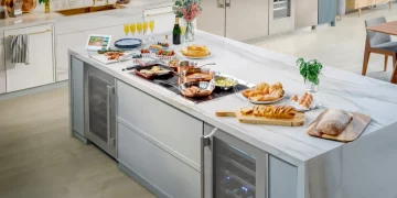 Modern Thermador kitchen featuring Liberty induction cooktop on marble island with integrated wine refrigerator and Freedom column refrigeration, showcasing complete appliance package eligible for free gifts promotion